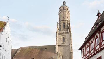 Ein historischer Turm mit einer Uhr, neben einem Gebäude mit traditioneller Fassade.