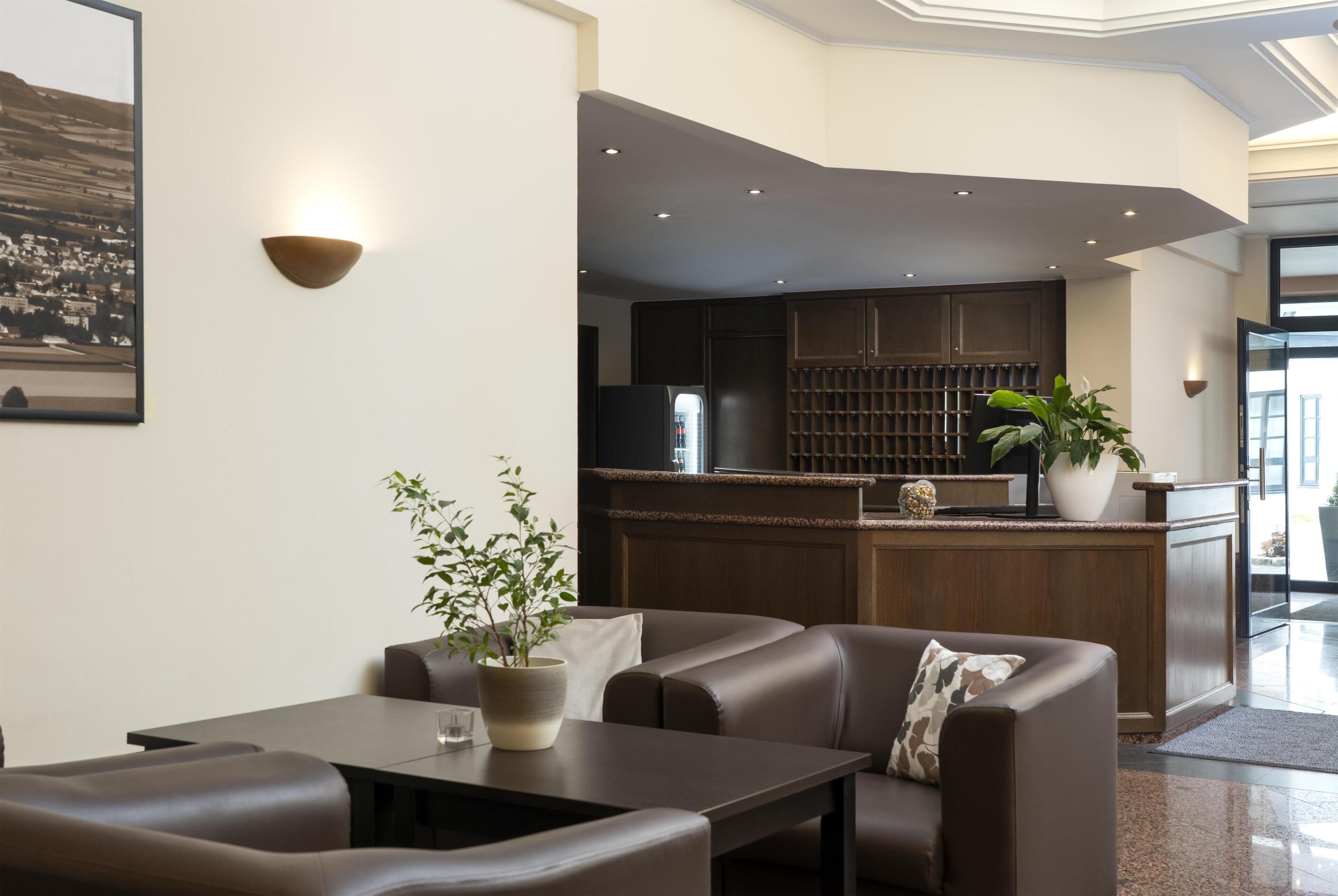 Un hall d’hôtel moderne doté d’un espace salon, d’un bar et offrant une vue sur la cuisine.
