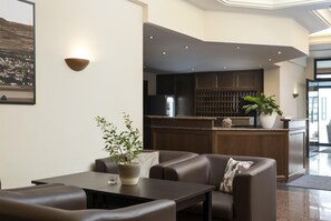 Un hall d’hôtel moderne doté d’un espace salon, d’un bar et offrant une vue sur la cuisine.