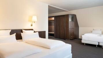 A hotel room with a large bed, a wardrobe, a desk, and a chair.