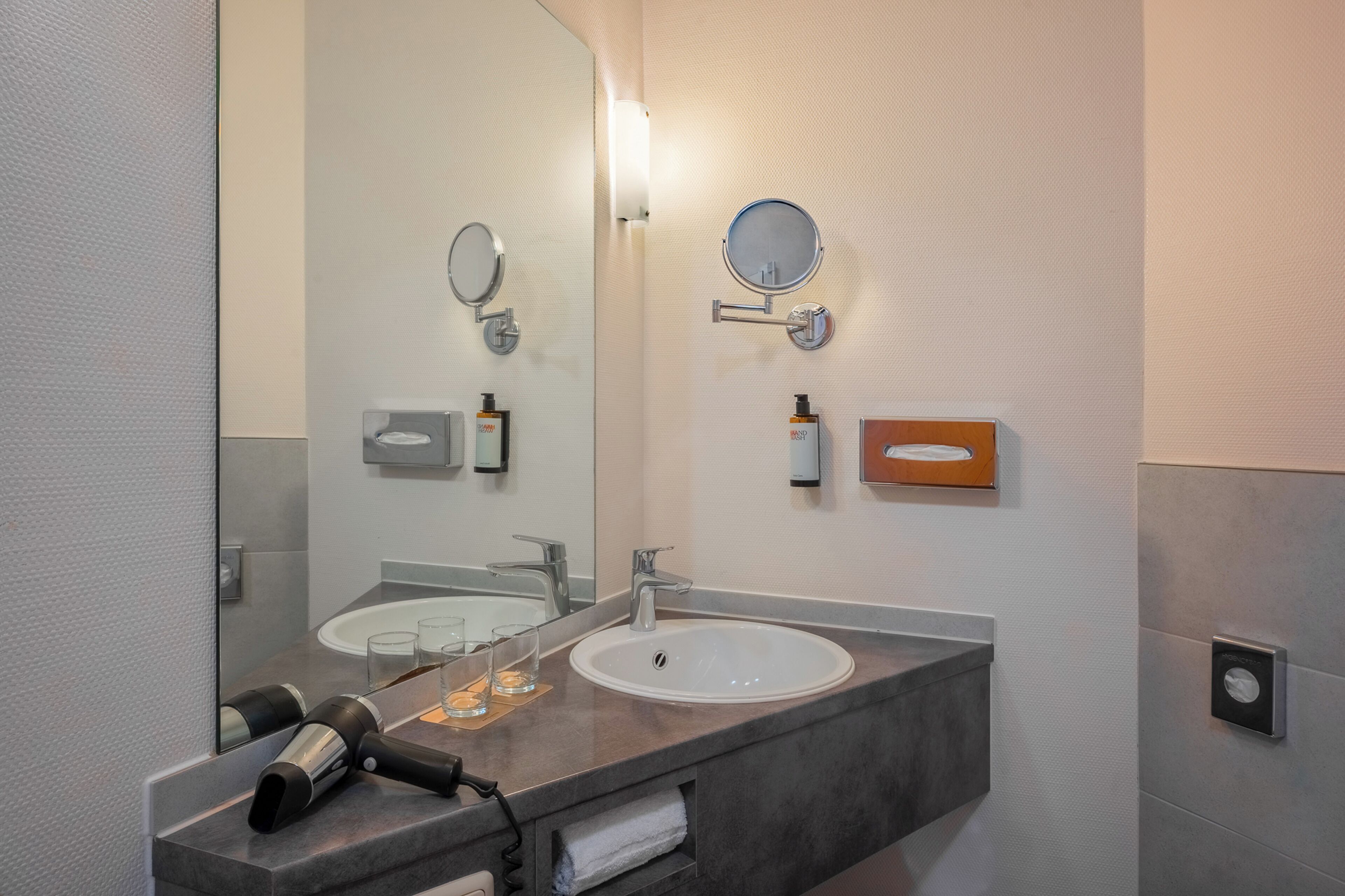 Een moderne badkamer met een grote spiegel, een wastafel en een handdoekhouder.