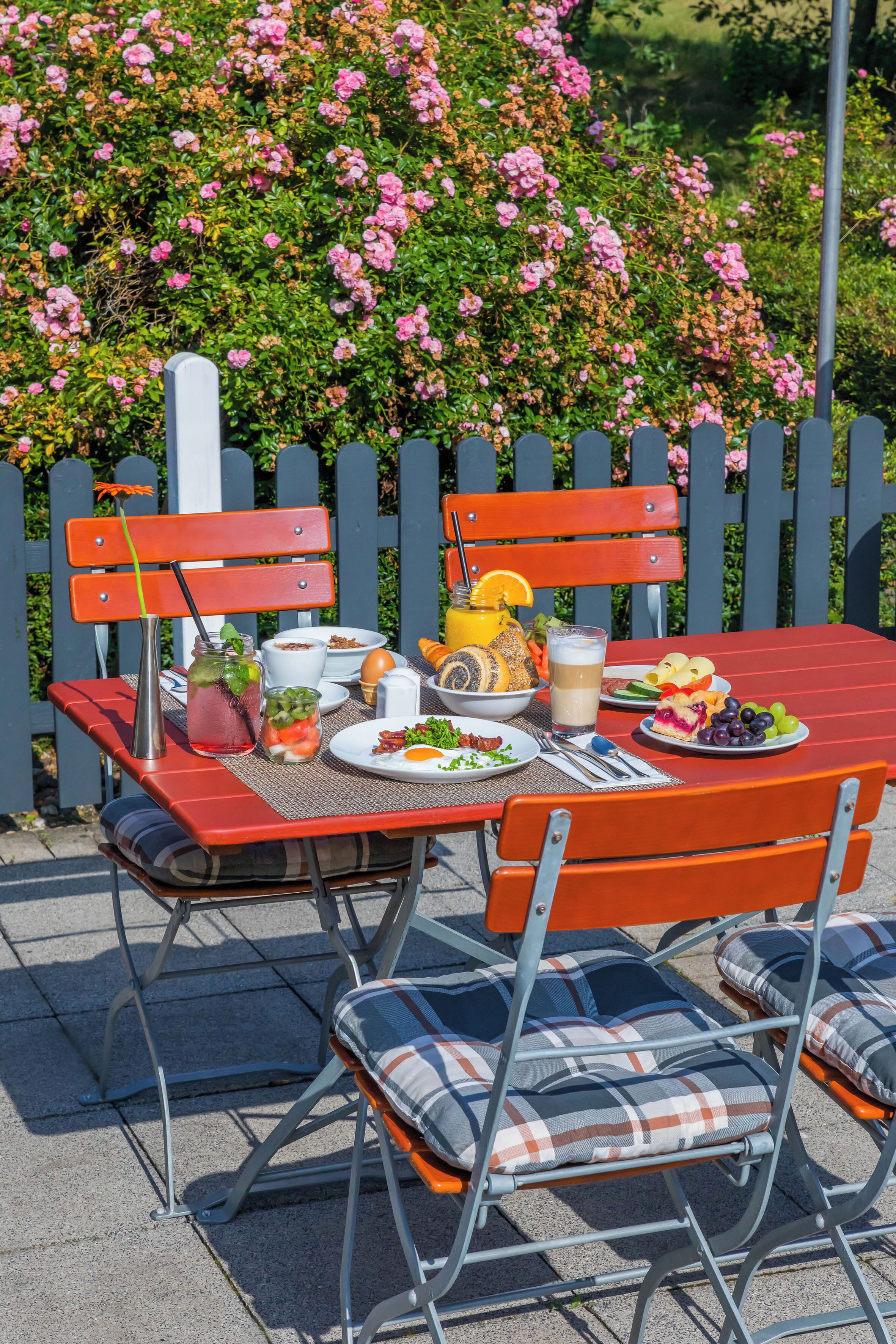 A picnic setup with a table, chairs, and a variety of food items.