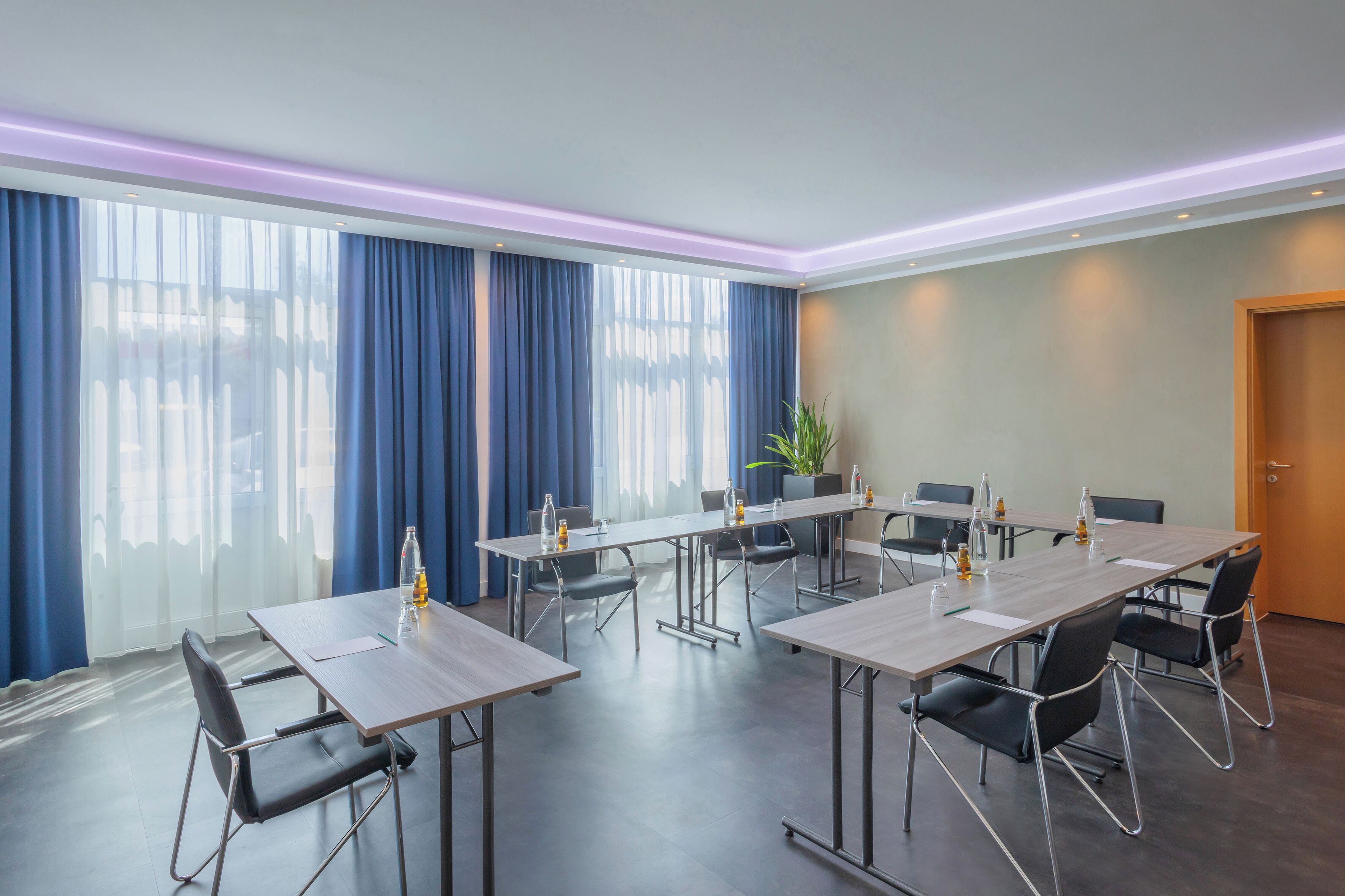 Ein Konferenzraum mit einem langen Tisch, Stühlen und einer Zimmerpflanze.