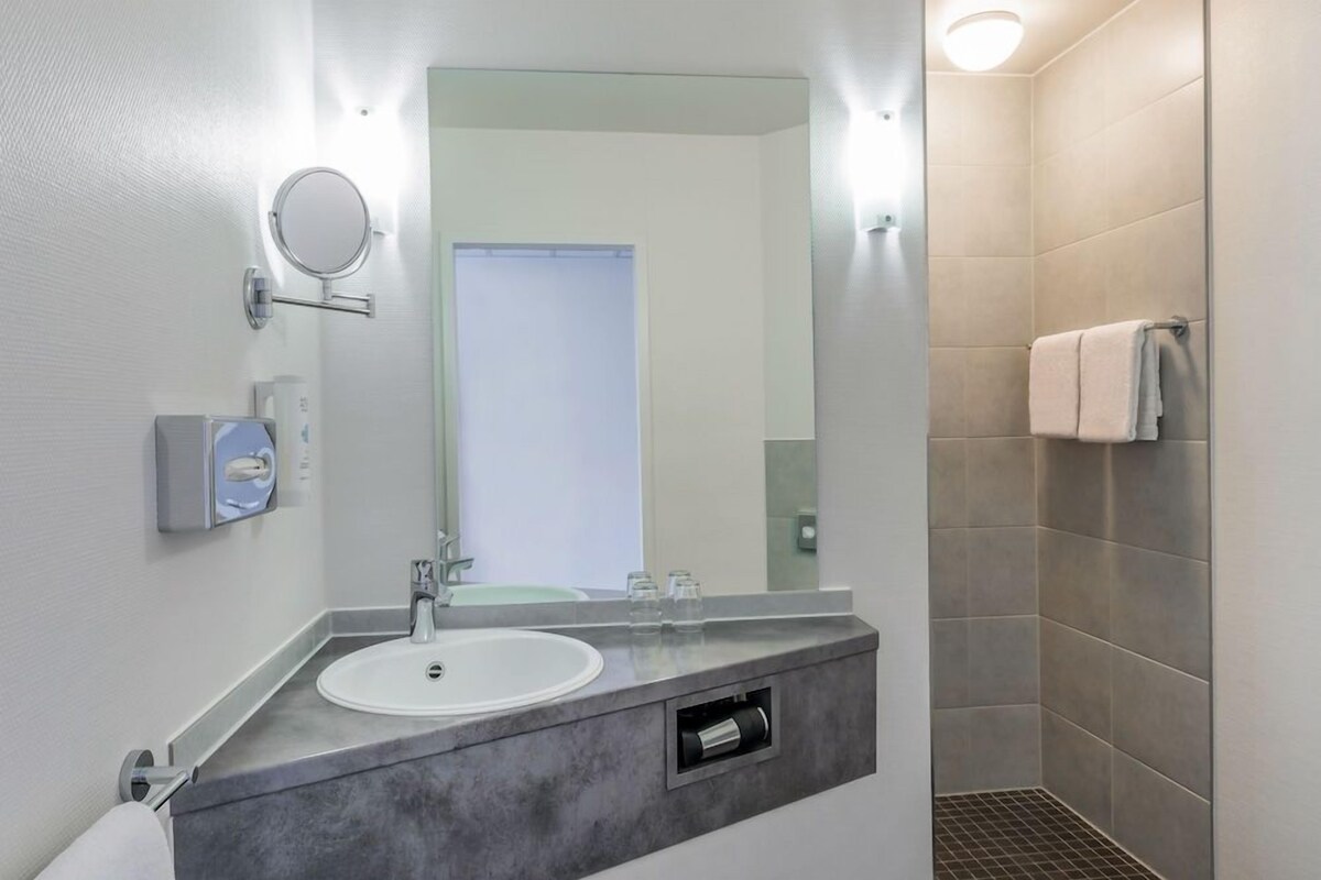 Une salle de bain moderne avec un lavabo, un miroir et une douche.