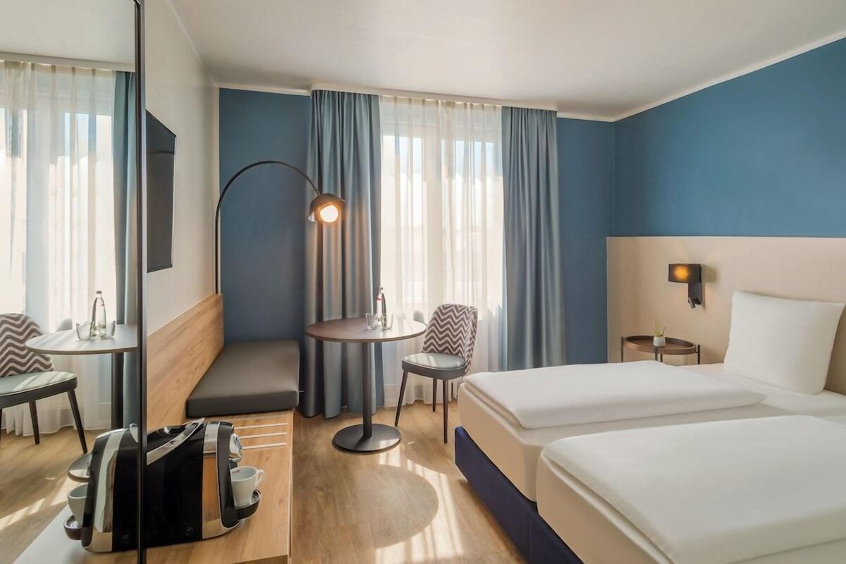 Een hotelkamer met een bed, een bureau, een stoel, een klein tafeltje en een bank.