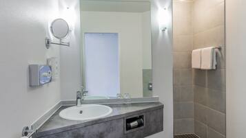 Ein modernes Badezimmer mit Waschbecken, Spiegel und Dusche.