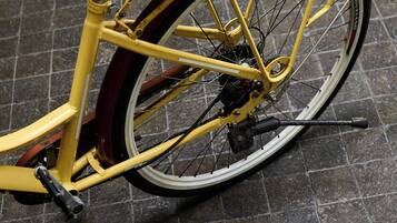 Una bicicleta estática con una cesta y un asiento, ubicada sobre un piso de baldosas.
