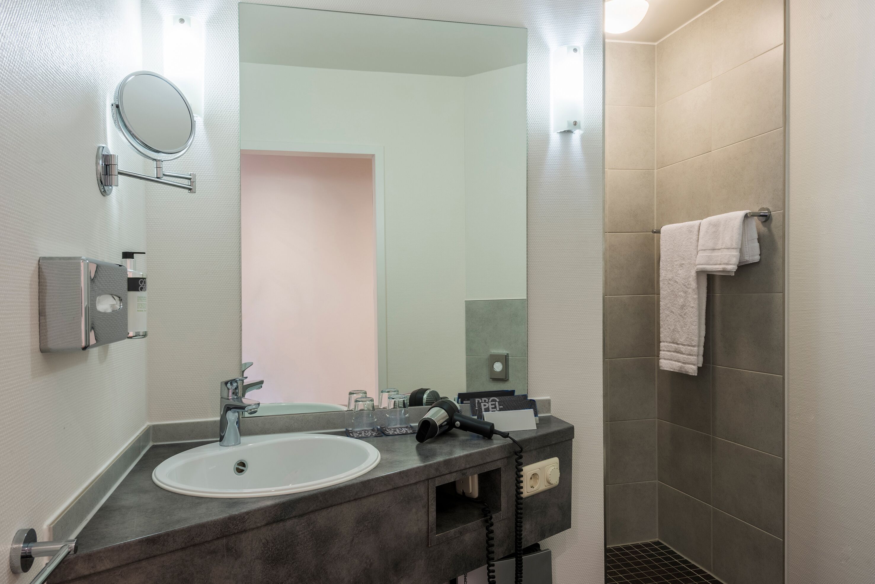 A modern bathroom with a sink, mirror, and shower.