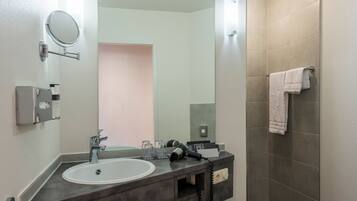 A modern bathroom with a sink, mirror, and shower.