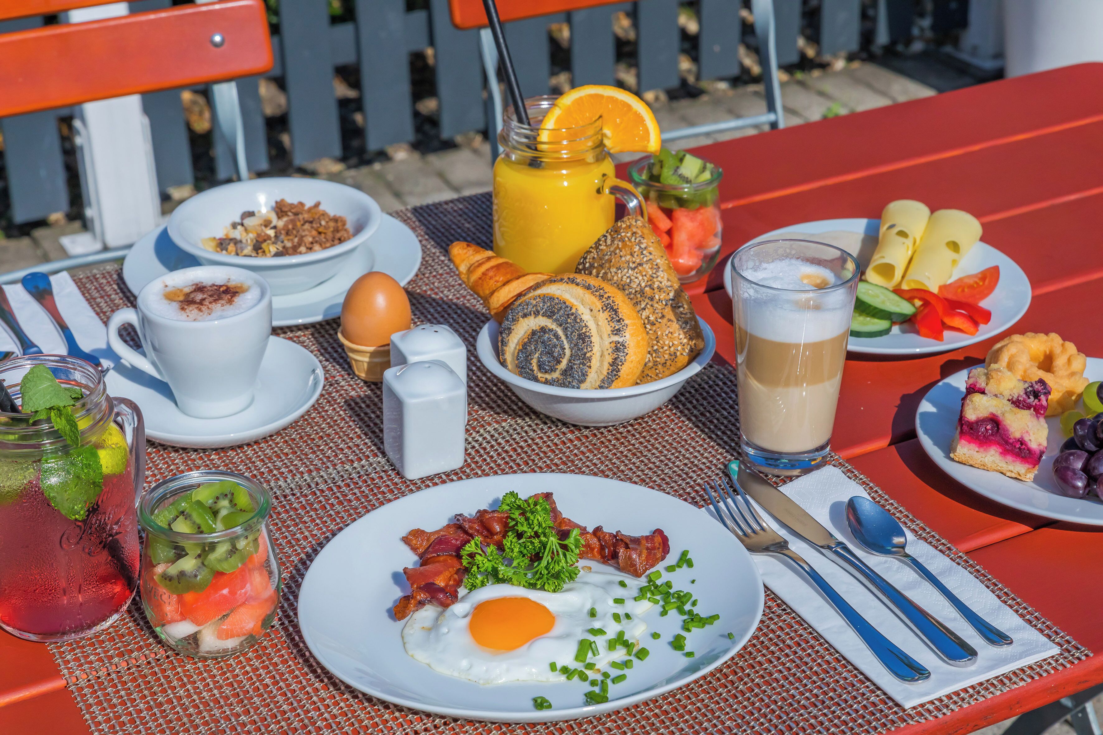 Une table de petit-déjeuner avec divers aliments, une boisson et des couverts.
