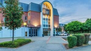 Ein Hotel mit modernem Design, das eine markante Bogenfassade und eine Ziegelwand aufweist.