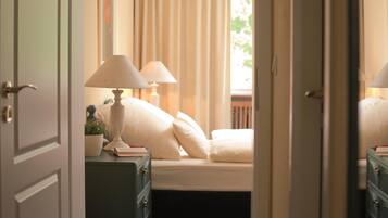 Une chambre à coucher avec un lit, deux lampes de chevet, une table de chevet avec une lampe et une fenêtre avec des rideaux.
