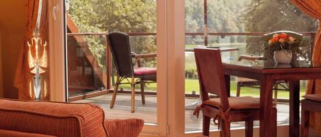 A balcony with a wooden table, chairs, and a sofa.