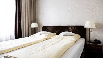 A double bed with two pillows, a bedside table with a lamp, and a wall with a textured pattern.