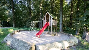 A playground with a wooden slide and climbing structure surrounded by trees. - Seehotel Frankenhorst - BW Signature Collection (Schwerin)