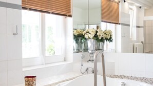A modern bathroom with a freestanding bathtub, a large mirror, and a window with blinds. - Seehotel Frankenhorst - BW Signature Collection (Schwerin)