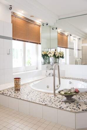 A modern bathroom with a freestanding bathtub, a large mirror, and a window with blinds. - Seehotel Frankenhorst - BW Signature Collection (Schwerin)