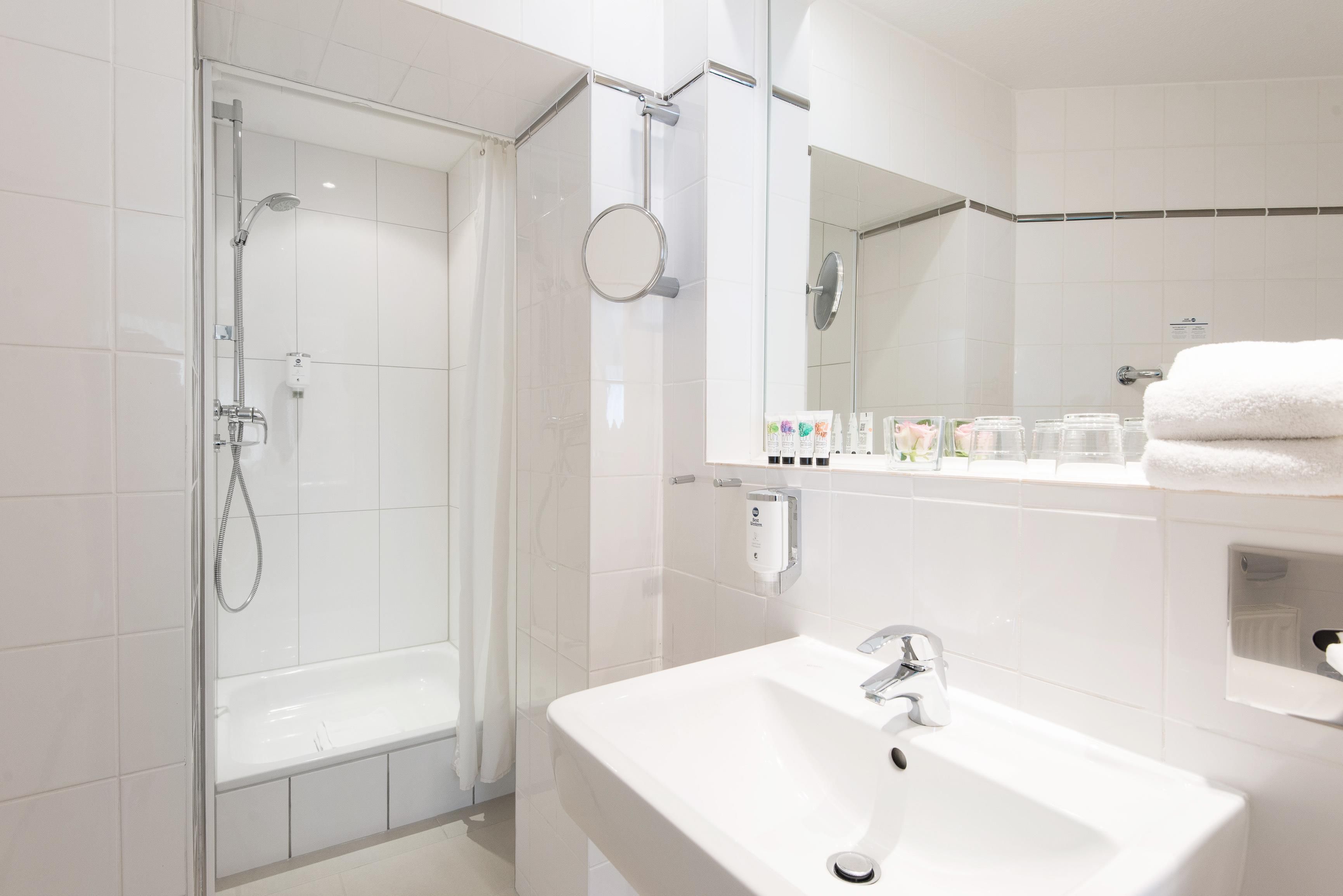 A modern bathroom with a glass-enclosed shower, a white sink, and a mirror above the sink.