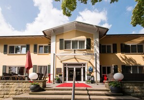 A hotel entrance with a red carpet, outdoor seating, and potted plants. - Seehotel Frankenhorst - BW Signature Collection (Schwerin)