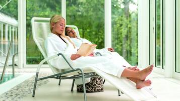 Relax in a tranquil space with a view of lush greenery, featuring a comfortable lounge chair and a glass door leading to another area.
