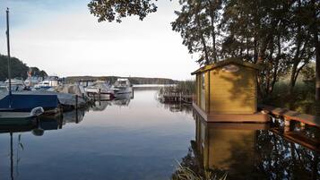A calm marina with boats docked, a wooden boathouse, and a clear sky.