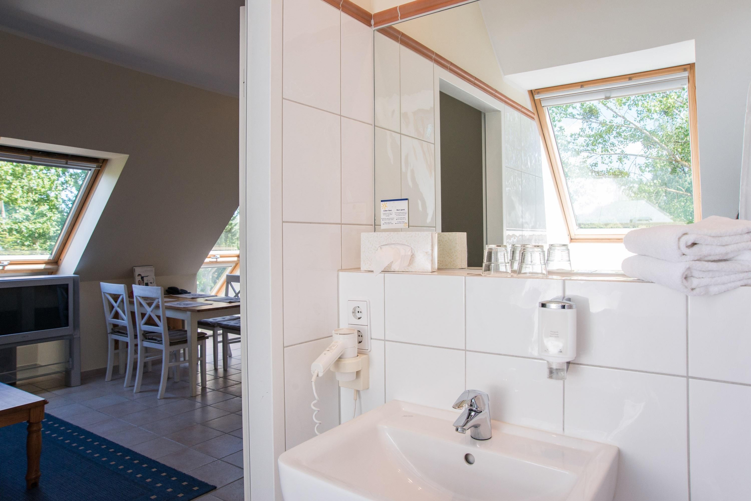 Un baño moderno con lavamanos, espejo y perchero para toallas.