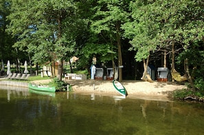 A riverside area with a green boat, lounge chairs, and a small building. - Seehotel Frankenhorst - BW Signature Collection (Schwerin)