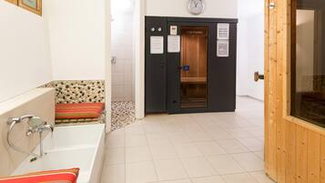 A bathroom with a bathtub, a shower, and a sauna door.