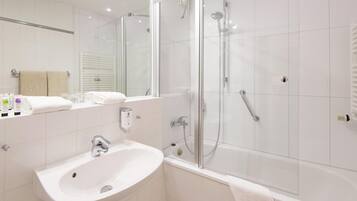 A modern bathroom with a white sink, a glass shower enclosure, and a large mirror.