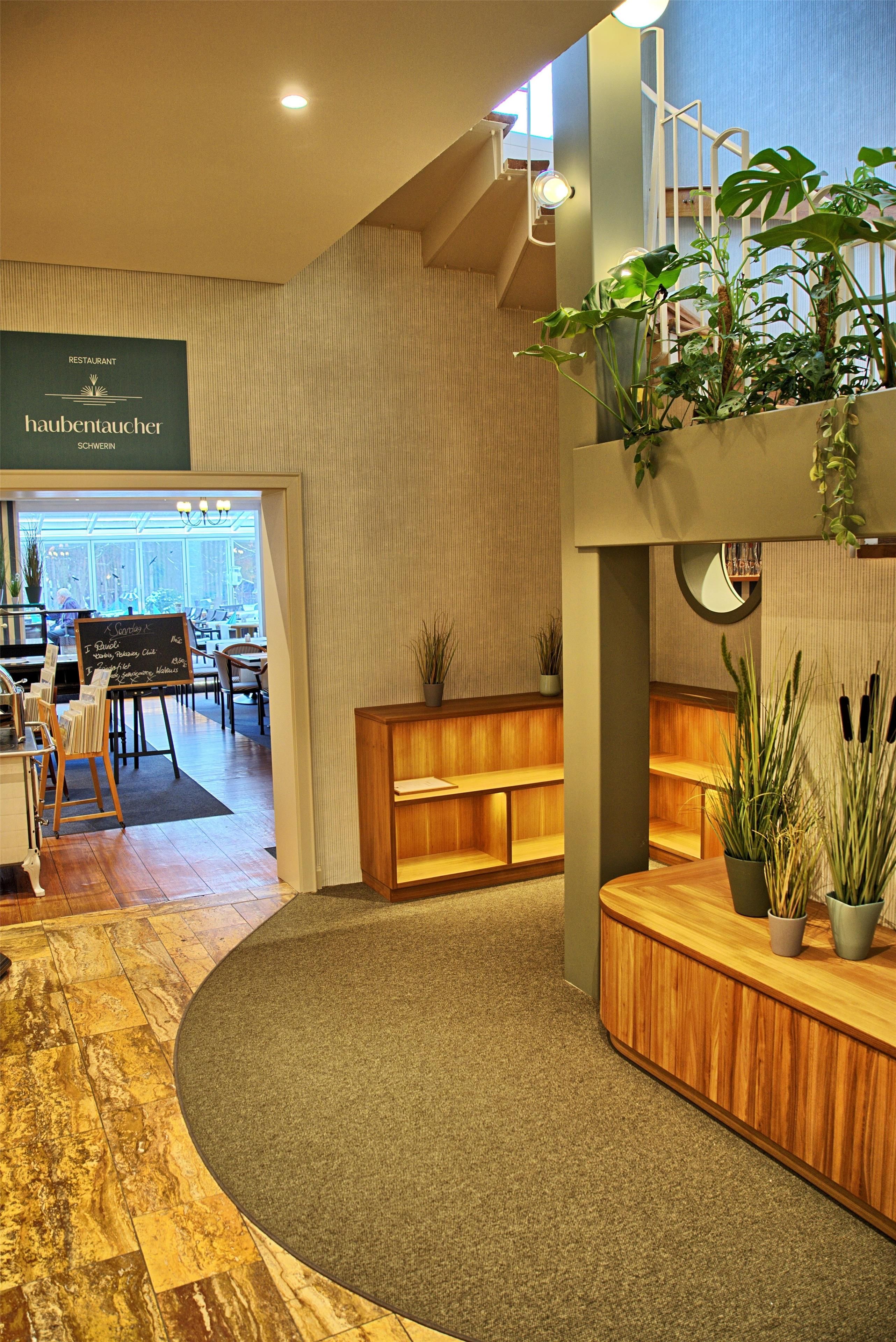 A restaurant interior with a wooden reception desk, seating area, and a chalkboard menu.