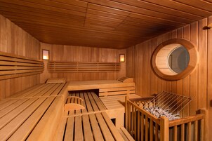 Una sauna con bancos de madera y un ventanal circular.