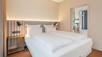 Una habitación de hotel moderna con una cama grande, una mesita de noche y una lámpara de pared.