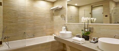 A modern bathroom with a bathtub, two sinks, a large mirror, and a towel rack.