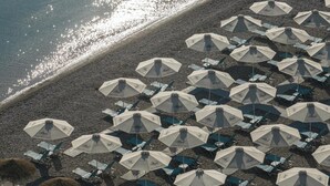 A beach with rows of umbrellas and chairs, likely for sunbathing. - Alkyon Resort Hotel & Spa (Velo-Vocha)