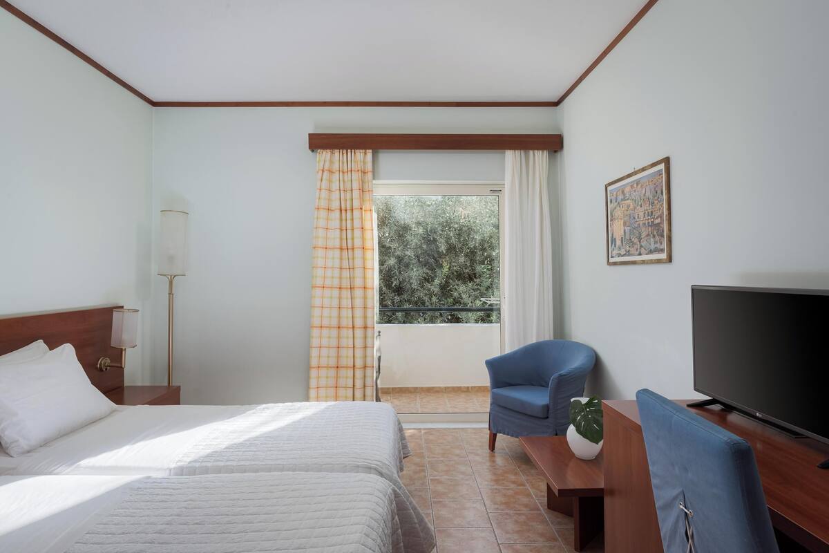 A hotel room with two beds, a TV, a desk, and a chair.