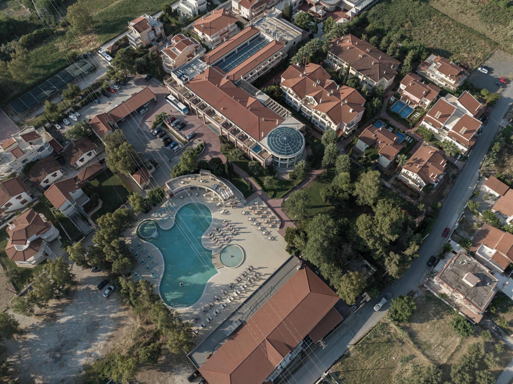 Vue aérienne d’un quartier r ésidentiel avec des maisons, une piscine et un bâtiment circulaire surmonté d’un dôme.
