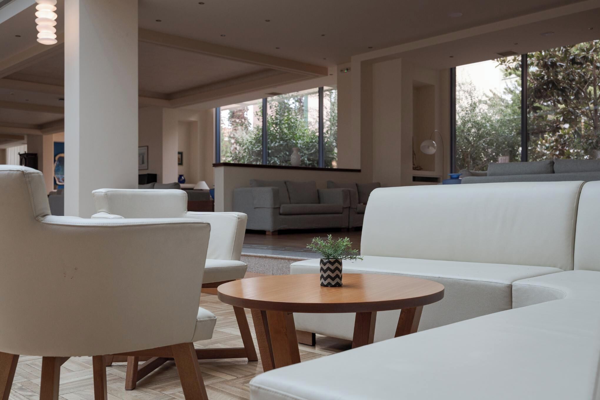 Un salon moderne avec un canapé blanc, une table ronde en bois et une plante en pot.