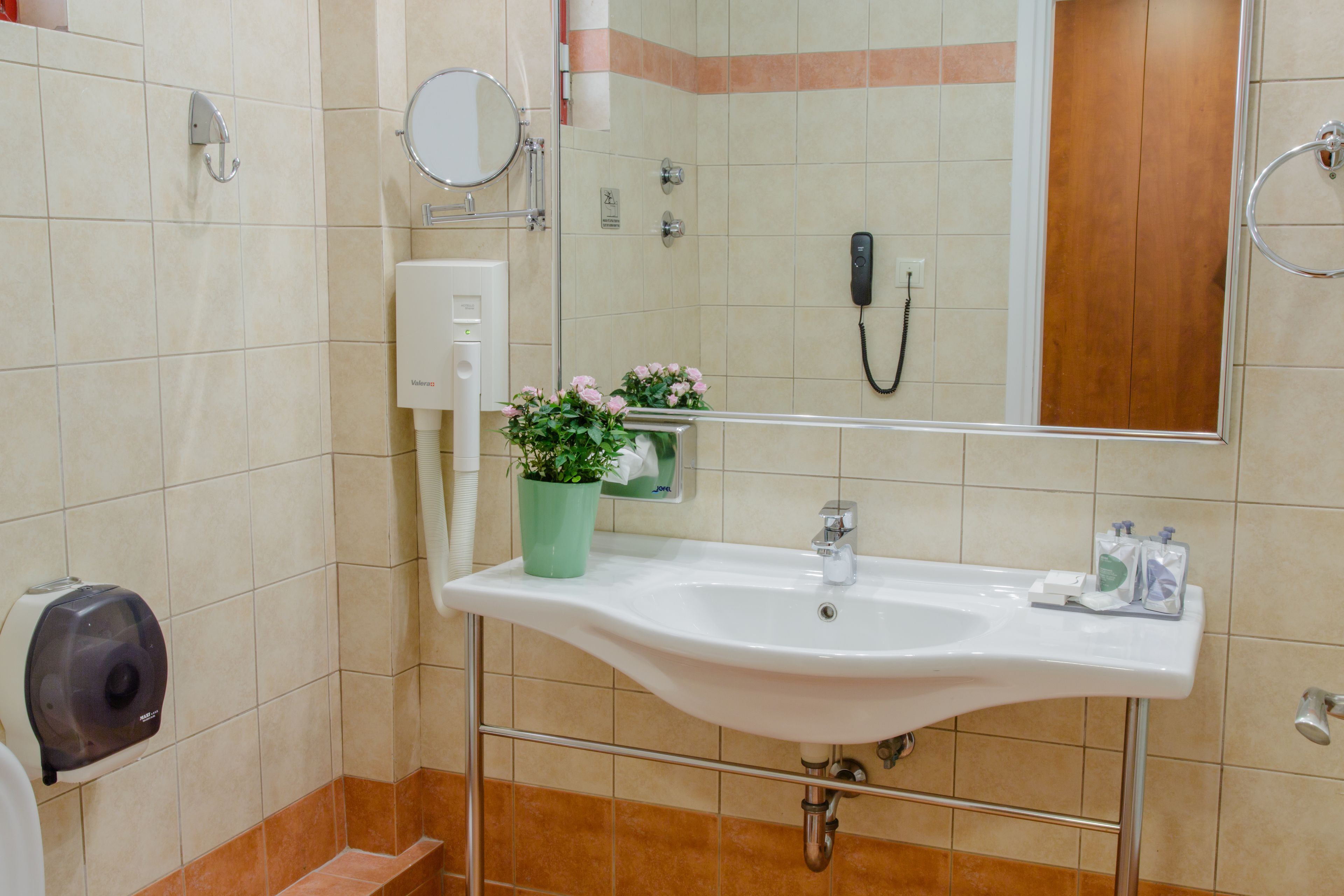 A bathroom with a sink, mirror, and a hand dryer.