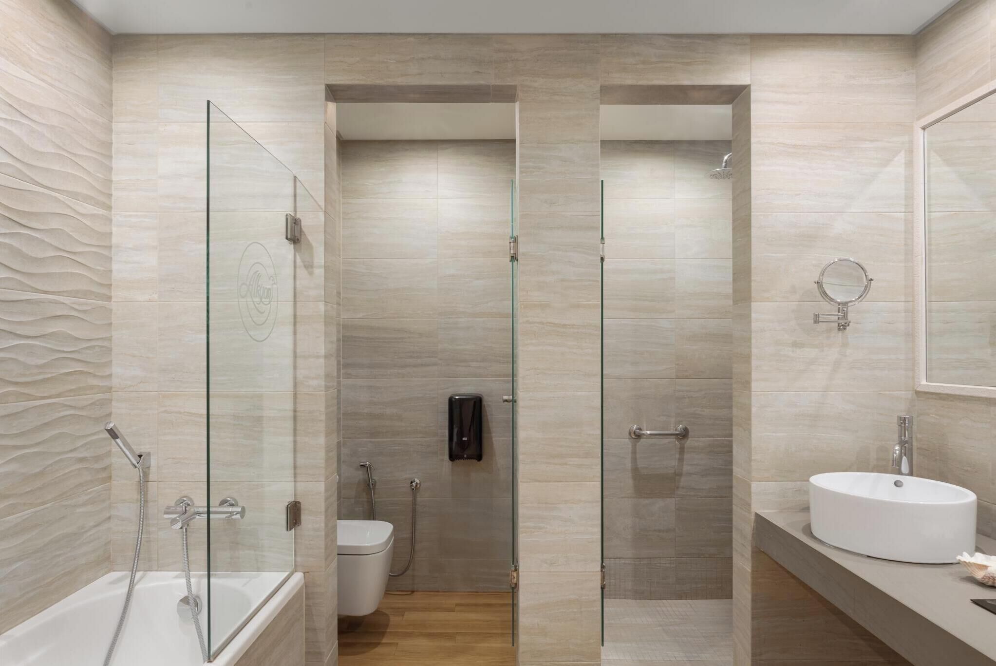 A modern bathroom with a glass-enclosed shower, a white sink, and a toilet.
