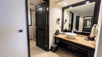 Un baño moderno con un espejo grande, un lavamanos blanco y una puerta negra.