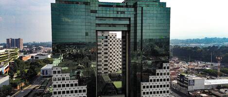Un moderno edificio de gran altura con un diseño arquitectónico distintivo, que presenta un hueco central y fachada de vidrio reflectante.