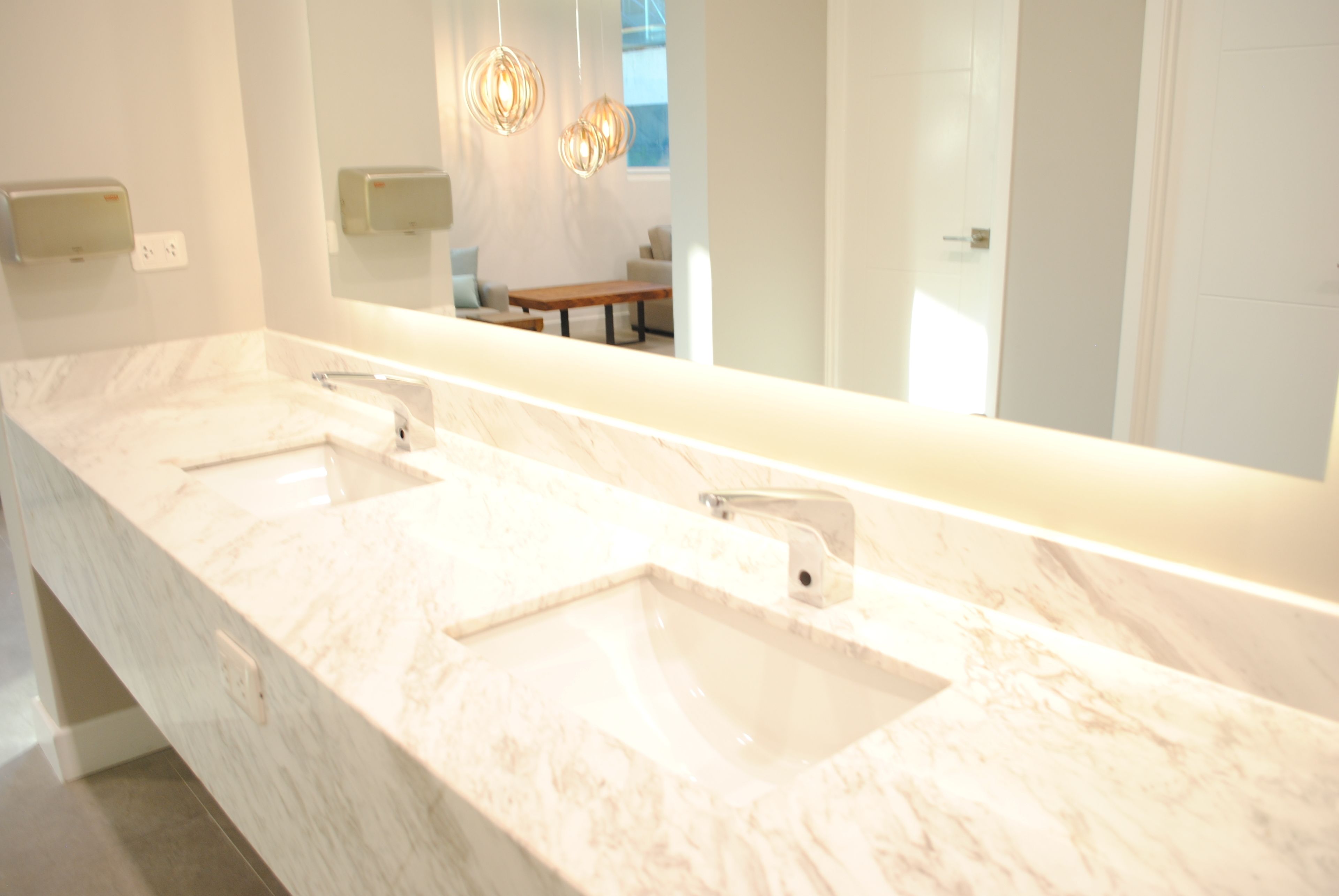 Un baño moderno con un espejo grande, dos lavamanos y una encimera de mármol.