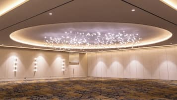 A spacious room with a patterned carpet, recessed lighting, and a modern chandelier.