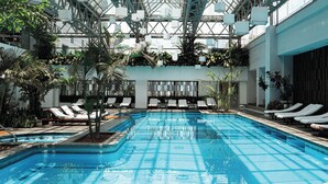 An indoor swimming pool with lounge chairs and potted plants.