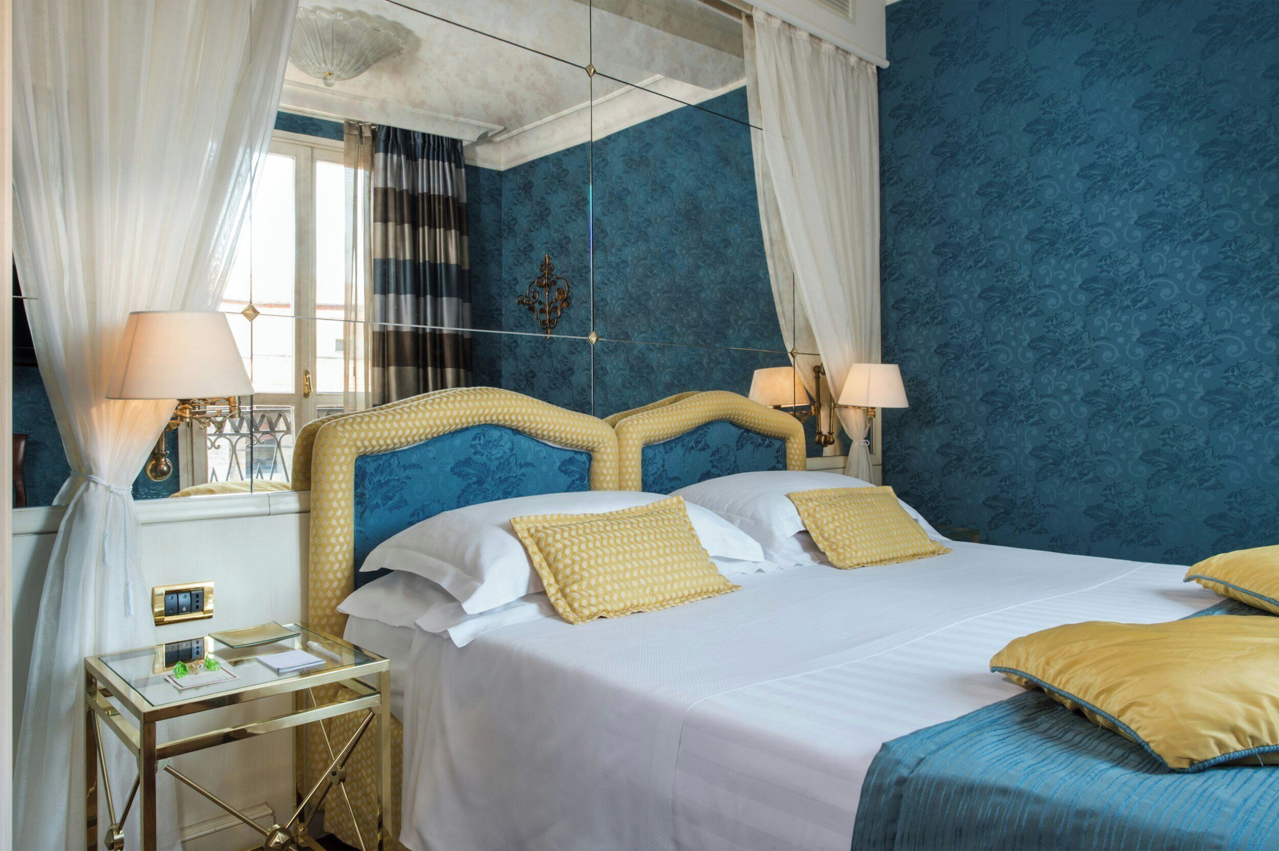 A hotel room with a bed, bedside tables, and curtains.