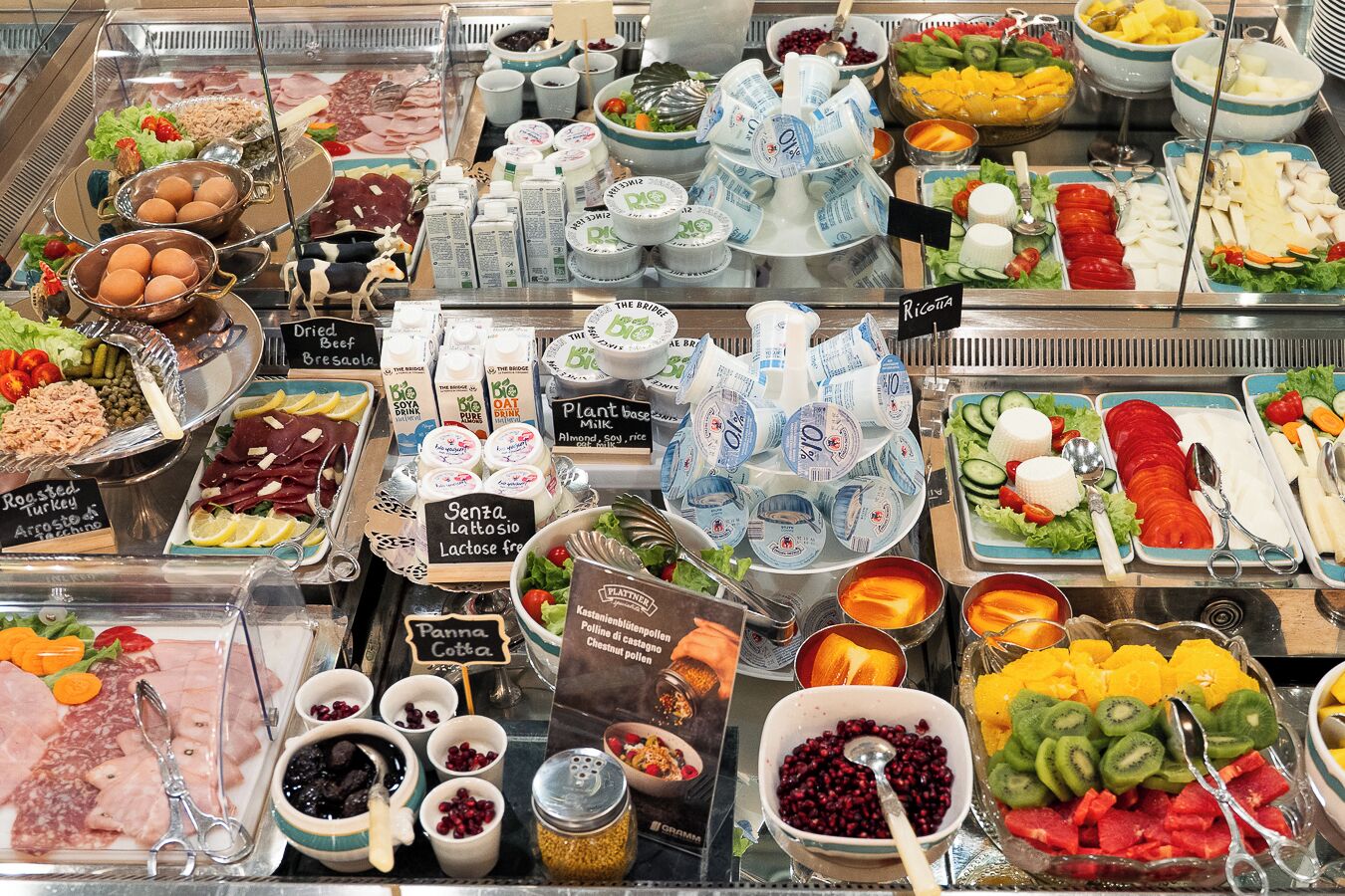 Variedad de alimentos, incluyendo carnes, quesos, frutas y productos lácteos, presentados en un bufé.