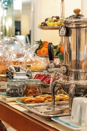 Ein Buffet mit verschiedenen Speisen, darunter Gebäck, Obst und einer Kaffeemaschine.