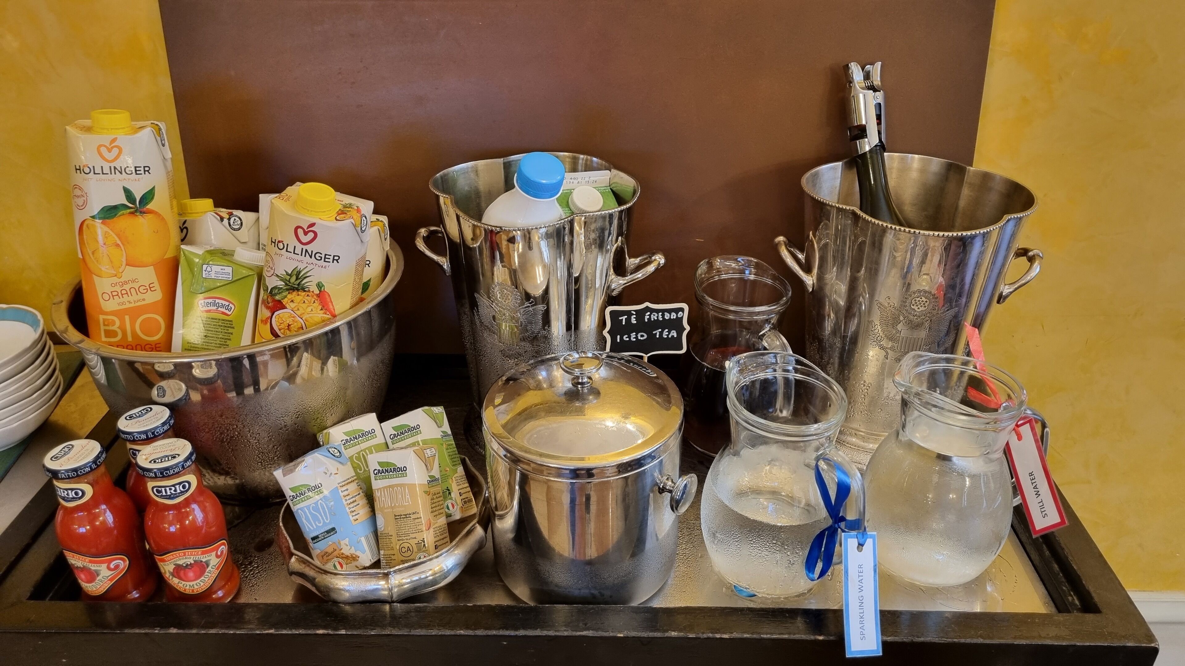 A variety of beverages and food items on a tray, including juice cartons, bottled water, and a pitcher labeled "iced tea".