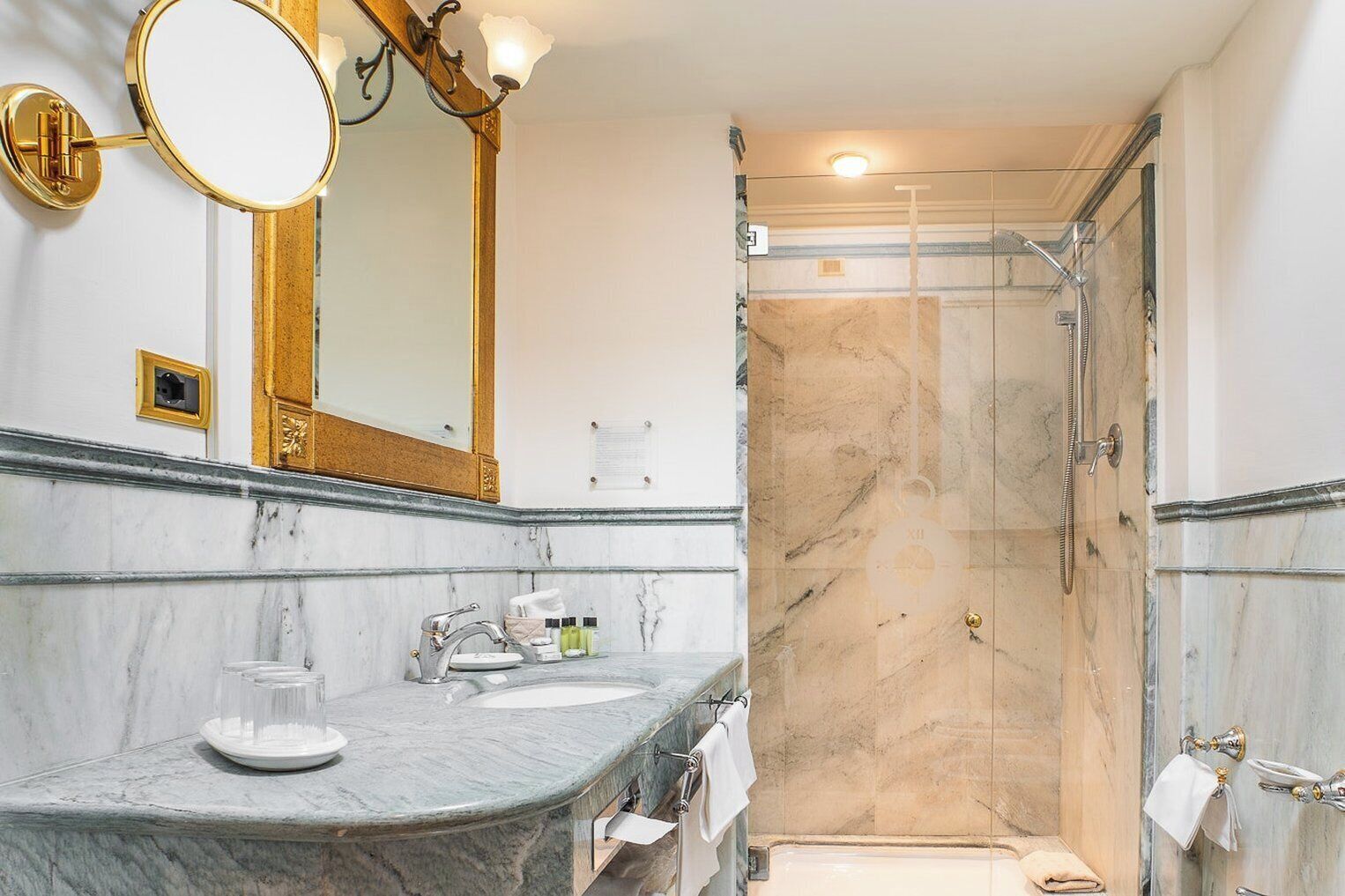 A bathroom with a marble vanity, a large mirror, a shower, and a toilet.