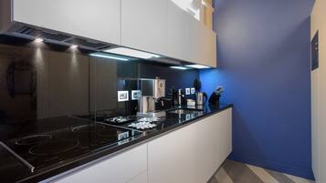 Una cocina moderna con estufa negra, armarios blancos y una pared azul de acento.